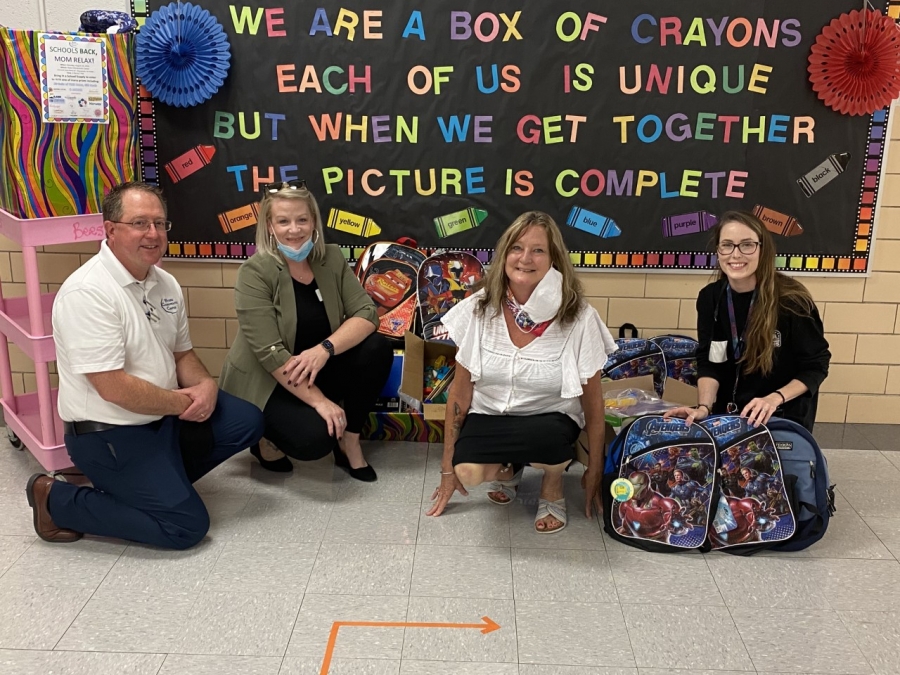 peoole kneeling in front of a colorful bulletin board